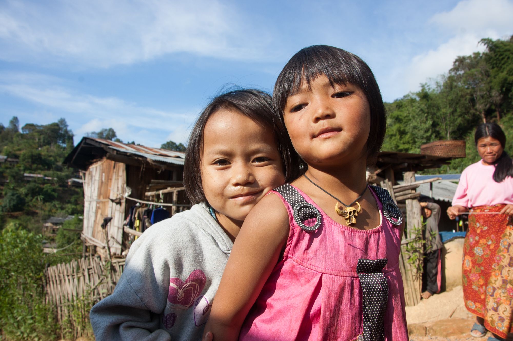 Portrait of cousins Viggo and Pimpisa in front of wooden hut